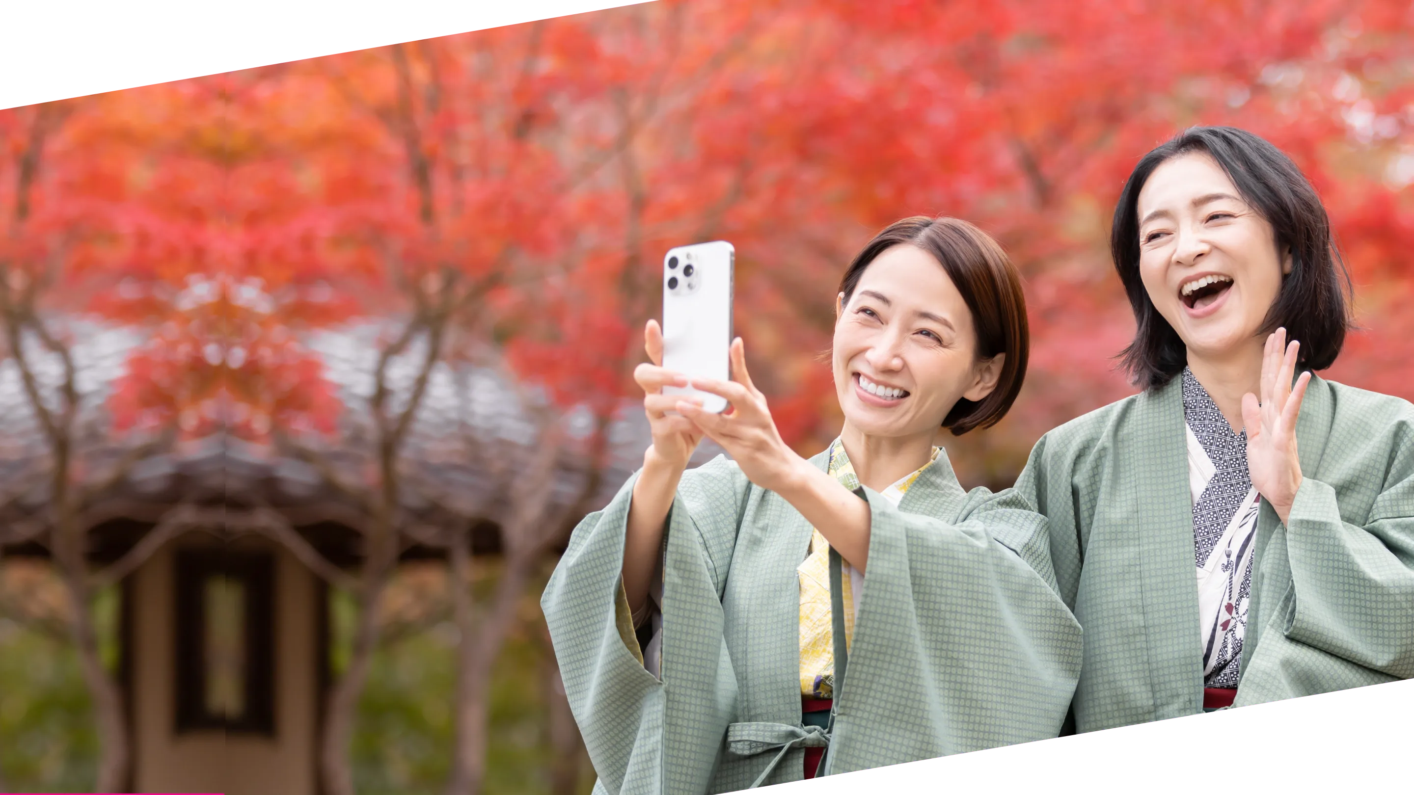 紅葉を背景にスマートフォンを手に笑顔を見せる2人の女性